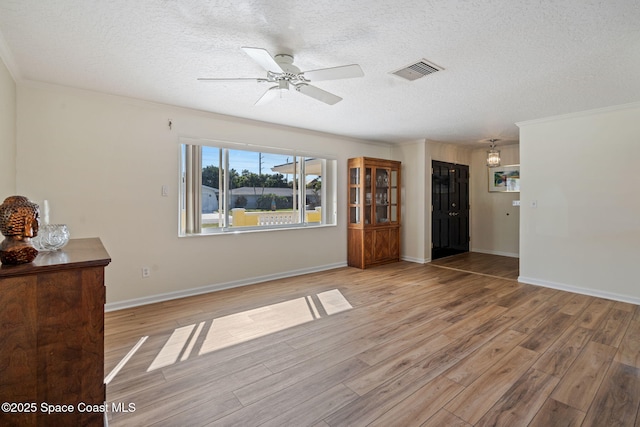 unfurnished living room with a textured ceiling, ceiling fan, ornamental molding, and wood-type flooring