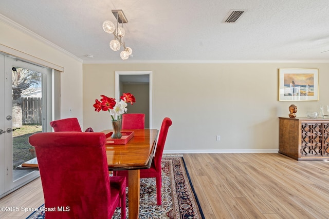 dining space with a textured ceiling, hardwood / wood-style floors, and crown molding