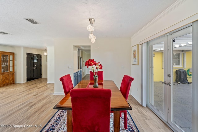 dining room featuring a textured ceiling, french doors, crown molding, and light hardwood / wood-style floors