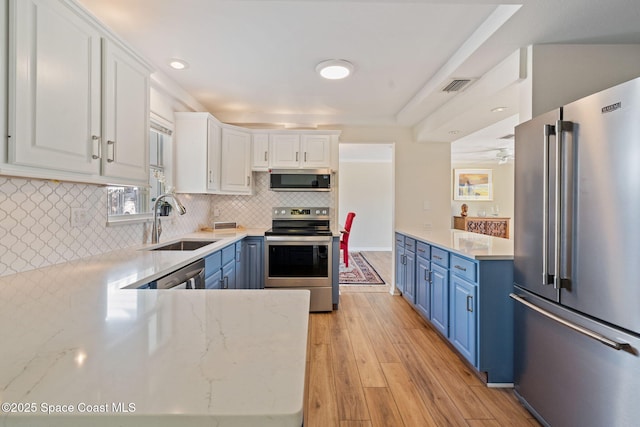 kitchen with white cabinets, stainless steel appliances, blue cabinets, and sink