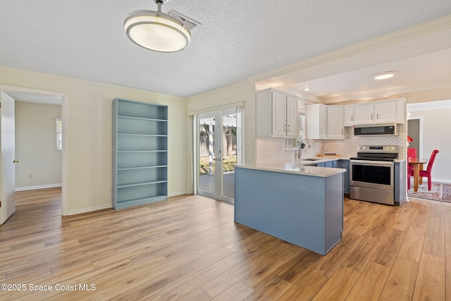 kitchen featuring stainless steel appliances, tasteful backsplash, light countertops, white cabinets, and light wood-type flooring