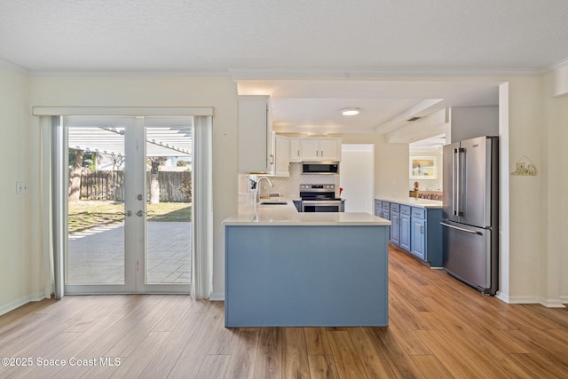 kitchen featuring light countertops, appliances with stainless steel finishes, ornamental molding, white cabinets, and blue cabinets