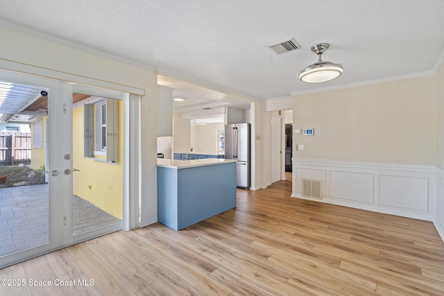 kitchen featuring visible vents, light countertops, light wood finished floors, and freestanding refrigerator