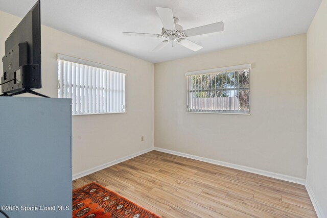 unfurnished room featuring a ceiling fan, baseboards, and light wood finished floors