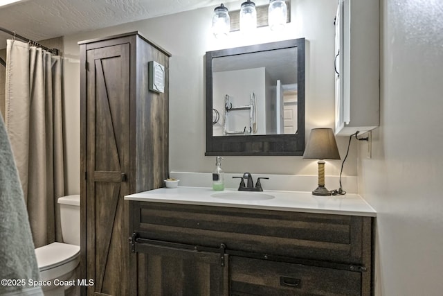 bathroom with vanity, toilet, a textured ceiling, and walk in shower