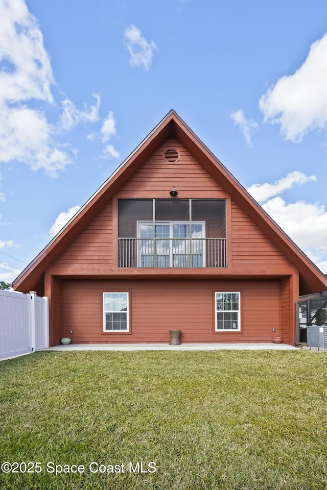 rear view of house with a yard, a patio area, and a balcony