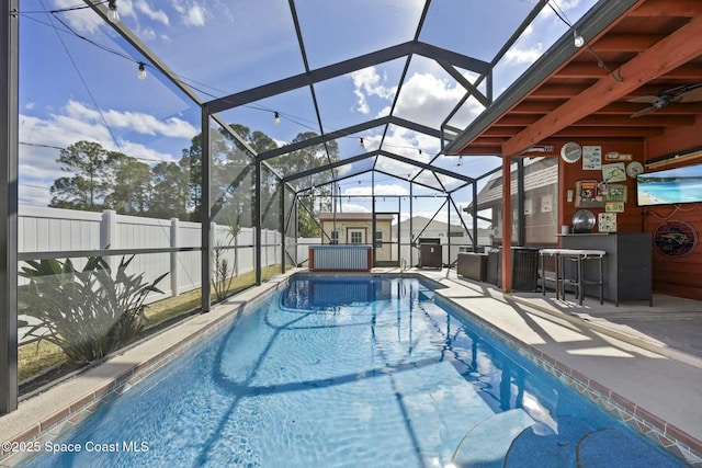 view of swimming pool featuring glass enclosure, exterior bar, a patio, and a jacuzzi