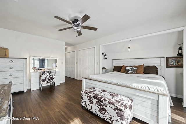 bedroom with multiple closets, ceiling fan, and dark wood-type flooring