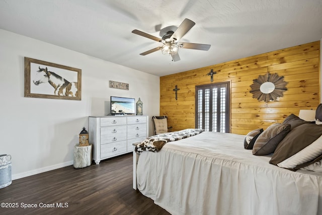 bedroom with wood walls, ceiling fan, dark wood-type flooring, and a textured ceiling