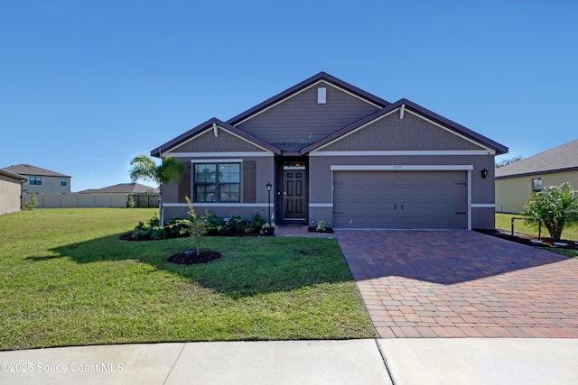 view of front of property with a garage, fence, decorative driveway, and a front yard