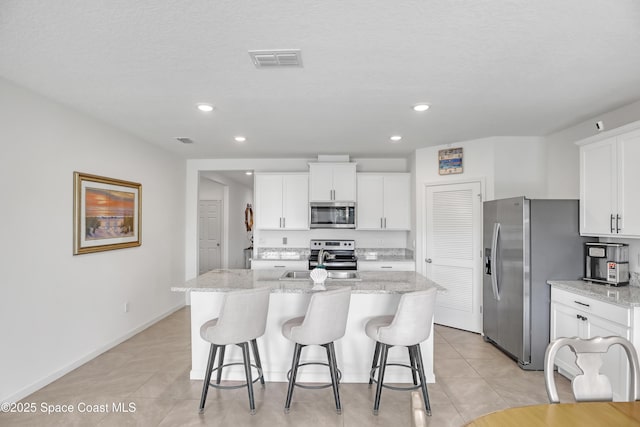 kitchen with appliances with stainless steel finishes, white cabinets, and a center island