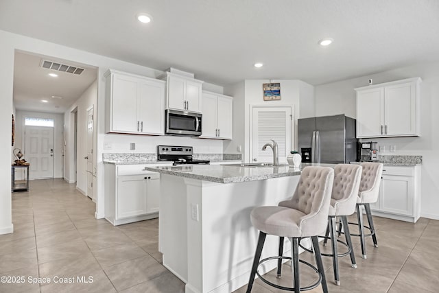 kitchen with stainless steel appliances, a kitchen island with sink, white cabinets, and sink