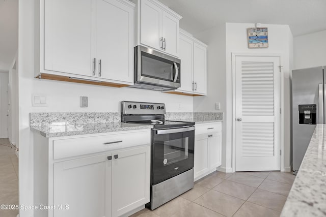 kitchen featuring light stone counters, stainless steel appliances, white cabinetry, and light tile patterned flooring