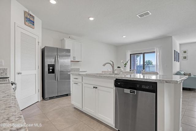 kitchen with stainless steel appliances, white cabinets, light tile patterned flooring, and sink