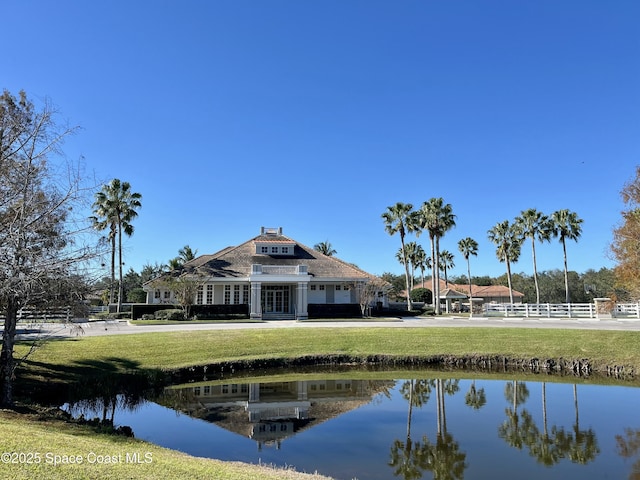 back of property with a water view and a lawn