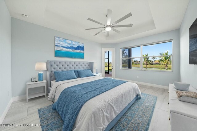 bedroom featuring access to exterior, ceiling fan, and a tray ceiling