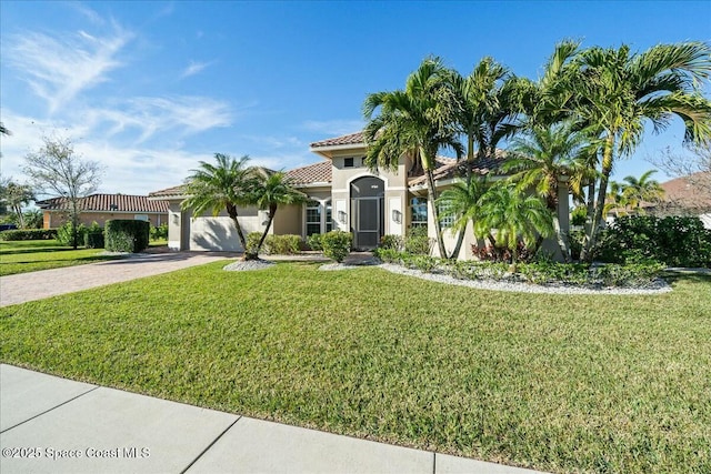 mediterranean / spanish-style house featuring a garage and a front lawn