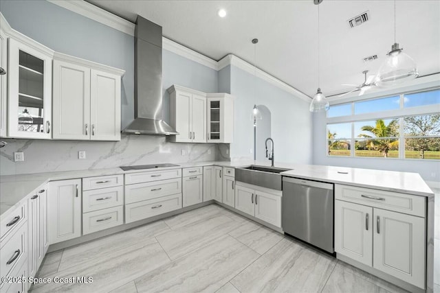 kitchen featuring sink, white cabinetry, decorative light fixtures, stainless steel dishwasher, and wall chimney range hood