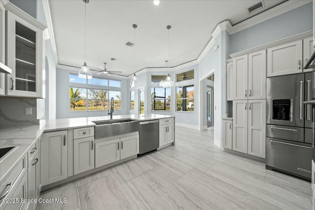 kitchen featuring pendant lighting, sink, ornamental molding, and stainless steel appliances