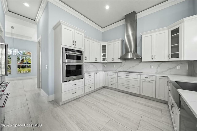 kitchen with backsplash, stainless steel double oven, black electric stovetop, and wall chimney range hood