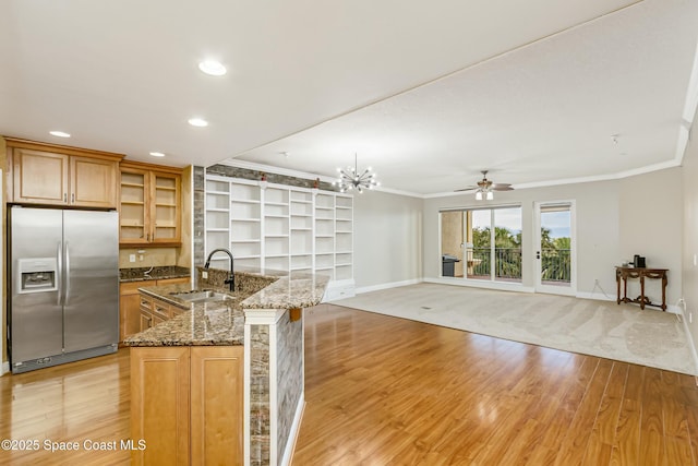 kitchen with light wood-style flooring, a sink, ornamental molding, dark stone countertops, and stainless steel fridge