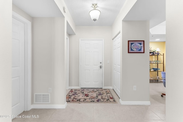 interior space with a textured ceiling and light tile patterned flooring