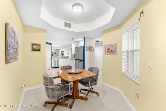 dining room featuring a textured ceiling and a tray ceiling