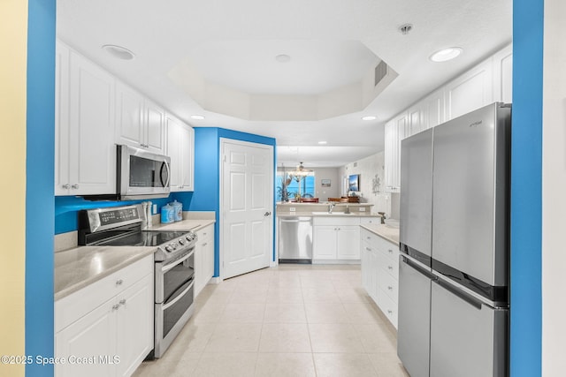 kitchen featuring a raised ceiling, appliances with stainless steel finishes, and white cabinetry