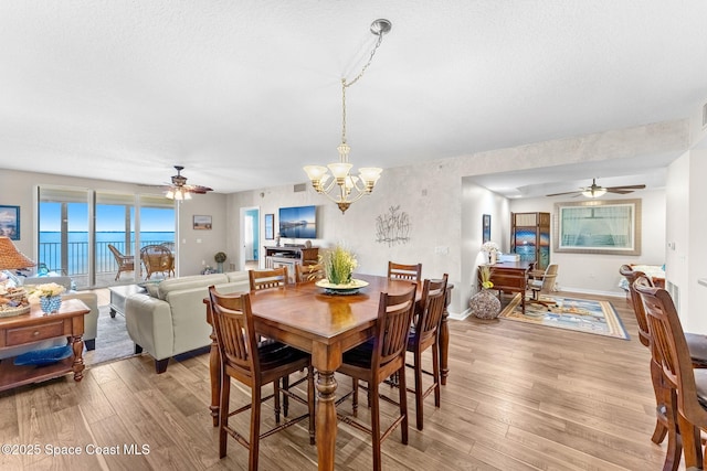 dining area featuring light hardwood / wood-style floors and ceiling fan with notable chandelier