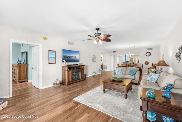 living room featuring ceiling fan with notable chandelier and wood-type flooring