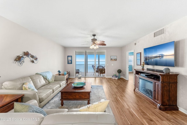 living room with ceiling fan and light hardwood / wood-style flooring