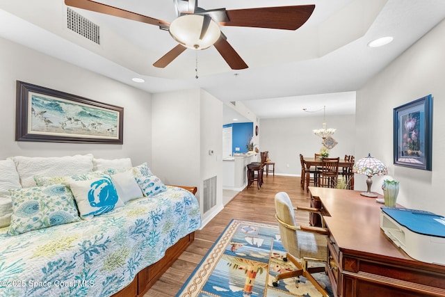 bedroom with ceiling fan with notable chandelier and wood-type flooring