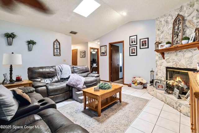 tiled living room with vaulted ceiling with skylight, a fireplace, and a textured ceiling