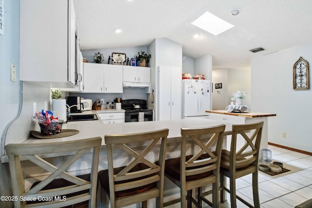 kitchen with lofted ceiling with skylight, white fridge, electric range, a textured ceiling, and white cabinets