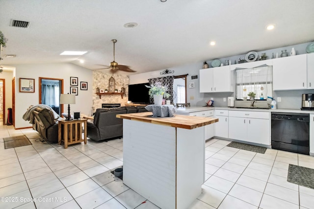 kitchen featuring a stone fireplace, ceiling fan, lofted ceiling, dishwasher, and white cabinets