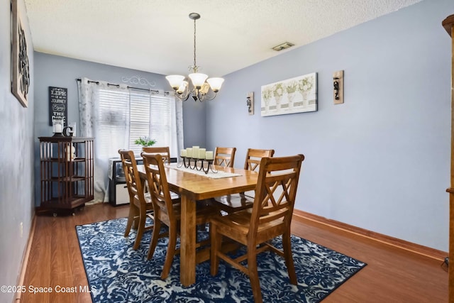 dining space featuring a textured ceiling, a chandelier, and dark hardwood / wood-style flooring