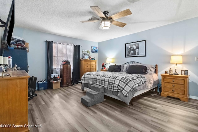 bedroom featuring ceiling fan, wood-type flooring, and a textured ceiling