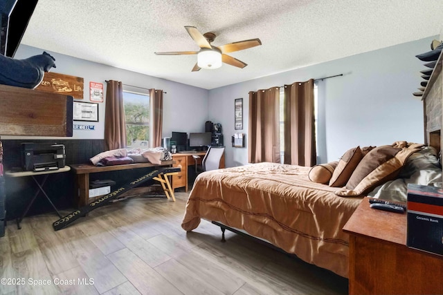 bedroom with ceiling fan, a textured ceiling, and light hardwood / wood-style flooring