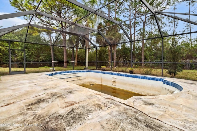 view of swimming pool featuring glass enclosure and a patio