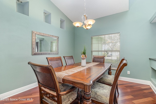 dining area with dark hardwood / wood-style flooring, vaulted ceiling, and a chandelier