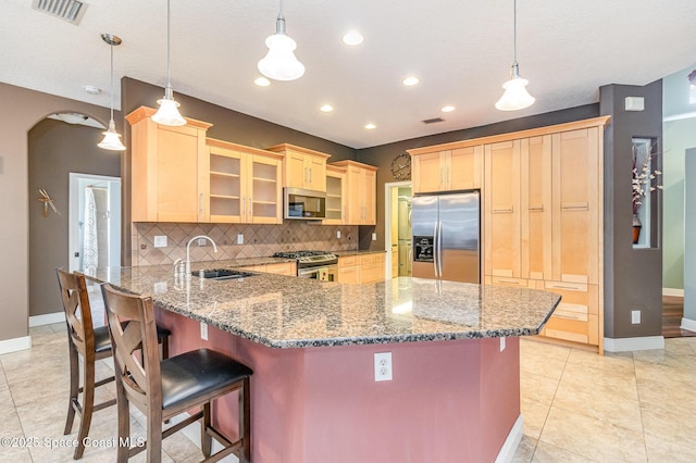 kitchen featuring sink, a breakfast bar, pendant lighting, and appliances with stainless steel finishes