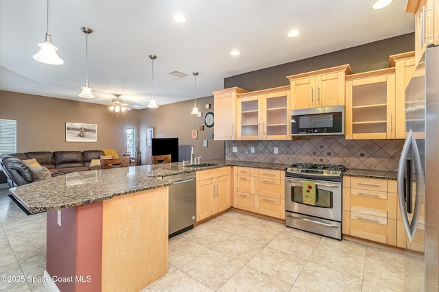 kitchen with light brown cabinets, pendant lighting, kitchen peninsula, and appliances with stainless steel finishes