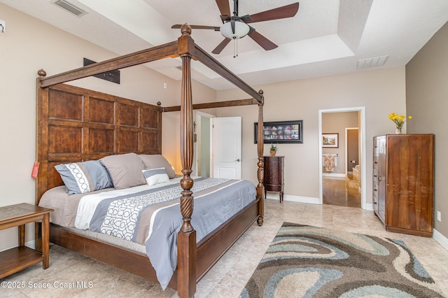 bedroom with connected bathroom, a raised ceiling, and ceiling fan