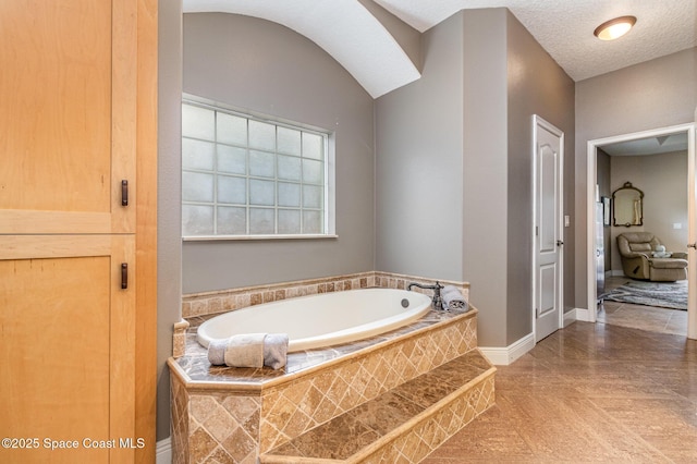 bathroom featuring a textured ceiling, tile patterned floors, and tiled tub