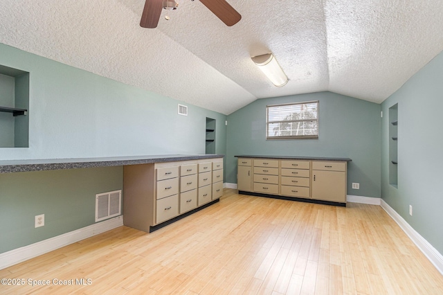 additional living space with a textured ceiling, lofted ceiling, ceiling fan, built in features, and light hardwood / wood-style flooring