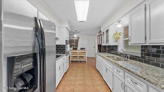 kitchen featuring tasteful backsplash, sink, light stone countertops, appliances with stainless steel finishes, and white cabinets