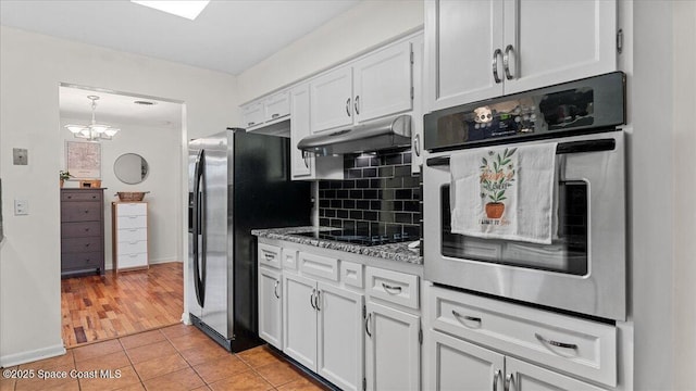 kitchen featuring decorative backsplash, light tile patterned floors, stainless steel appliances, white cabinets, and light stone counters