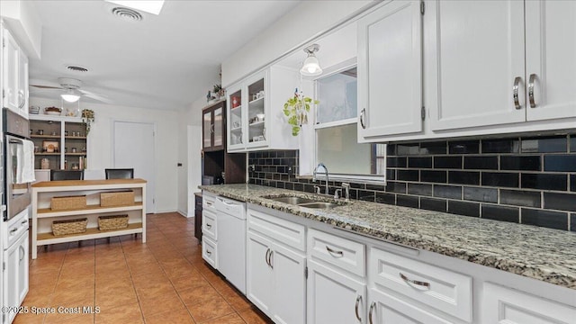 kitchen featuring white dishwasher, sink, white cabinetry, and tasteful backsplash