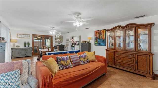 living room featuring a textured ceiling, a wealth of natural light, light tile patterned flooring, and french doors