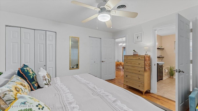 bedroom with ceiling fan, connected bathroom, multiple closets, and light wood-type flooring